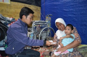 Gambar: Rosmiati yang sedang menggendong anaknya yang lumpuh akibat kelainan tularng lering, Anggi Ridho, saat menerima bantuan dari Edi Santosa, salah seorang sutradara film tersebut. (Foto: Fajri)