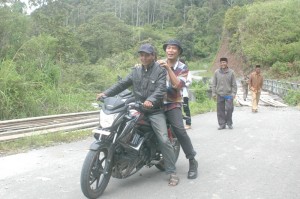 Naik sepeda motor, terlihat Adam Gergel Piraq menaiki sepeda motor, saat mengecek lokasi jembatan yang putus. 