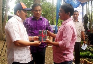 Ketua Dewan Kesenian Aceh (DKA) Kota Langsa Agusni AH (kanan) menyerahkan buku puisi penyair Aceh “Merengkuh Asa” kepada Wakil Walikota Langsa Marzuki Hamid saat peluncuran buku tersebut pada acara Langsa Green Festival yang diselenggarakan Disbudpar Kota Langsa di kawasan hutan lindung, Langsa, Sabtu (6/12/2014). (Foto: IST.)